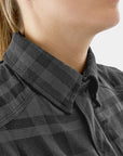 Close-up of a person wearing a black checkered shirt with a blurred background