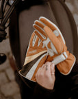 women's hands over a motorcycle gas tank while putting on colourful leather gloves from WILDUST