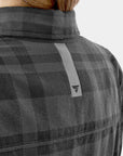 Person wearing a gray checkered jacket with a brand logo on a light gray background