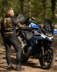 a blond woman standing by her big motorcycle wearing a black and gold mesh motorcycle jacket for women
