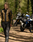 a blond smiling woman walking away from her motorcycle wearing a black and gold mesh motorcycle jacket for women