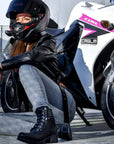 a woman by her sports bike wearing black leather motorcycle boot