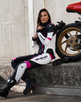Young woman wearing black, white, pink SHIMA motorcycle leather suit with her red motorcycle