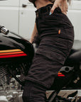 Half body of a woman siting on a motorcycle and wearing black motorcycle cargo pants from moto girl with big pockets s