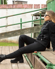 A woman wearing black boots, black mc jacket and black womens motorcycle pants with a front zip from Moto Girl