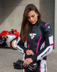 Young woman wearing black, white, pink SHIMA motorcycle leather suit with her red motorcycle