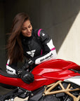 Young woman wearing black, white, pink SHIMA motorcycle leather suit with her red motorcycle