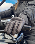 Person wearing a black glove on a motorcycle with a blue sky background