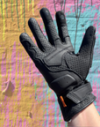 Black glove on a hand against a colorful, textured background