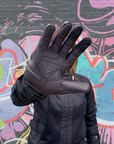 Person wearing a black glove against a colorful graffiti wall.