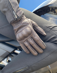 Beige motorcycle glove on a person sitting on a motorcycle with a clear blue sky background