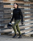 a woman wearing slim fit khaki green lady motorcycle jeans walking with her motorcycle helmet in hand