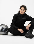 a motorcyclist sitting on the floor wearing black shirt looking lady motorcycle jacket with front pockets and zippers