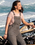 A woman by the beach with her motorcycle wearing grey women's motorcycle overall from Moto Girl