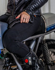 Half body of a woman siting on a motorcycle wearing black lady motorcycle leggings from MotoGirl