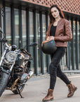 A young woman by a motorcycle wearing brown motorcycle leather jacket and brown women motorcycle boots from Shima