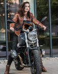 A young woman by a motorcycle wearing brown motorcycle leather jacket and brown women motorcycle boots from Shima