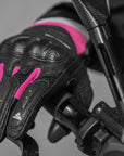 A hand on a motorcycle stearing wheel wearing Black and pink women's motorcycle gloves Rush lady from Shima