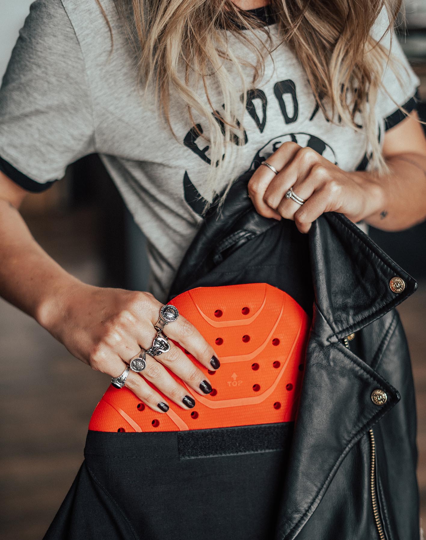 A blond woman taking out a back protector from women's motorcycle leather jacket