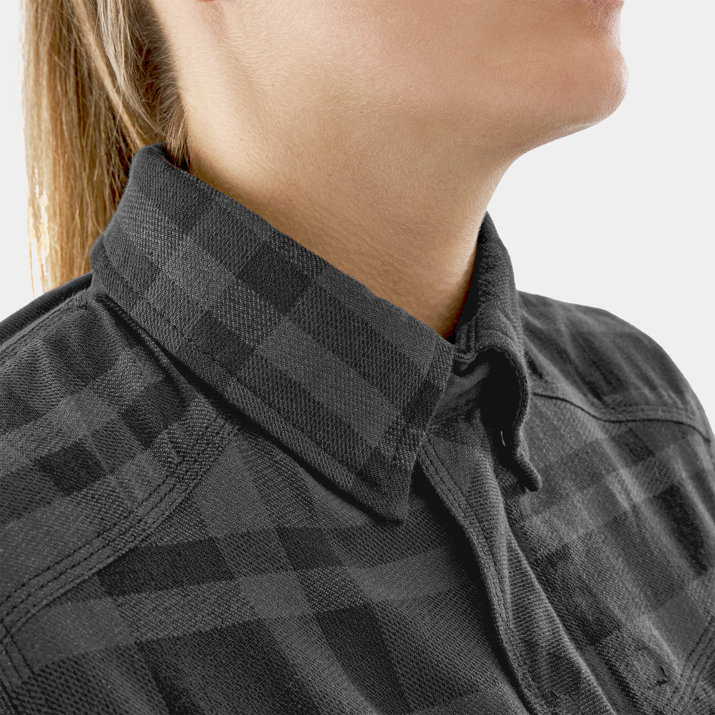 Close-up of a person wearing a black checkered shirt with a blurred background