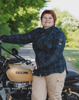 Person standing next to a Honda motorcycle in a natural setting wearing blue shima renegade motorcycle shirt for women