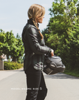 Person holding a helmet on a road with trees in the background