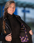 a young woman opening her Black retro style woman's motorcycle jacket with silver zip details