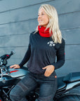 Blonde woman sitting on a motorcycle, wearing a Pando Moto t-shirt and a red knitted neck warmer from Moto Girl.