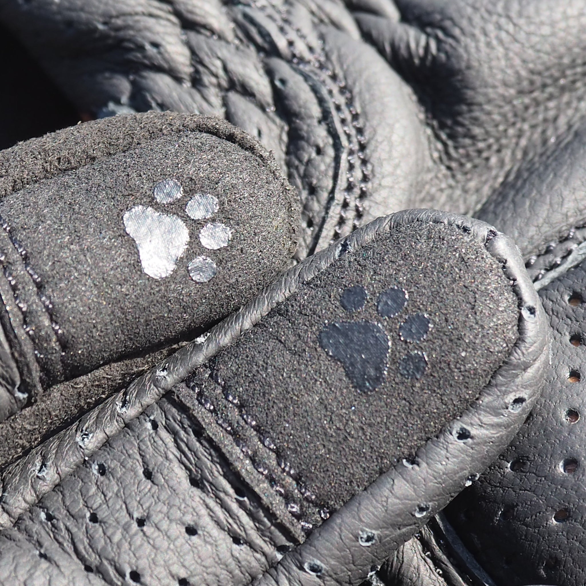 Close-up of gray leather shoes with paw print designs on the soles.