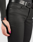 Person wearing black mc pants with a belt, holding a black strap against a white background