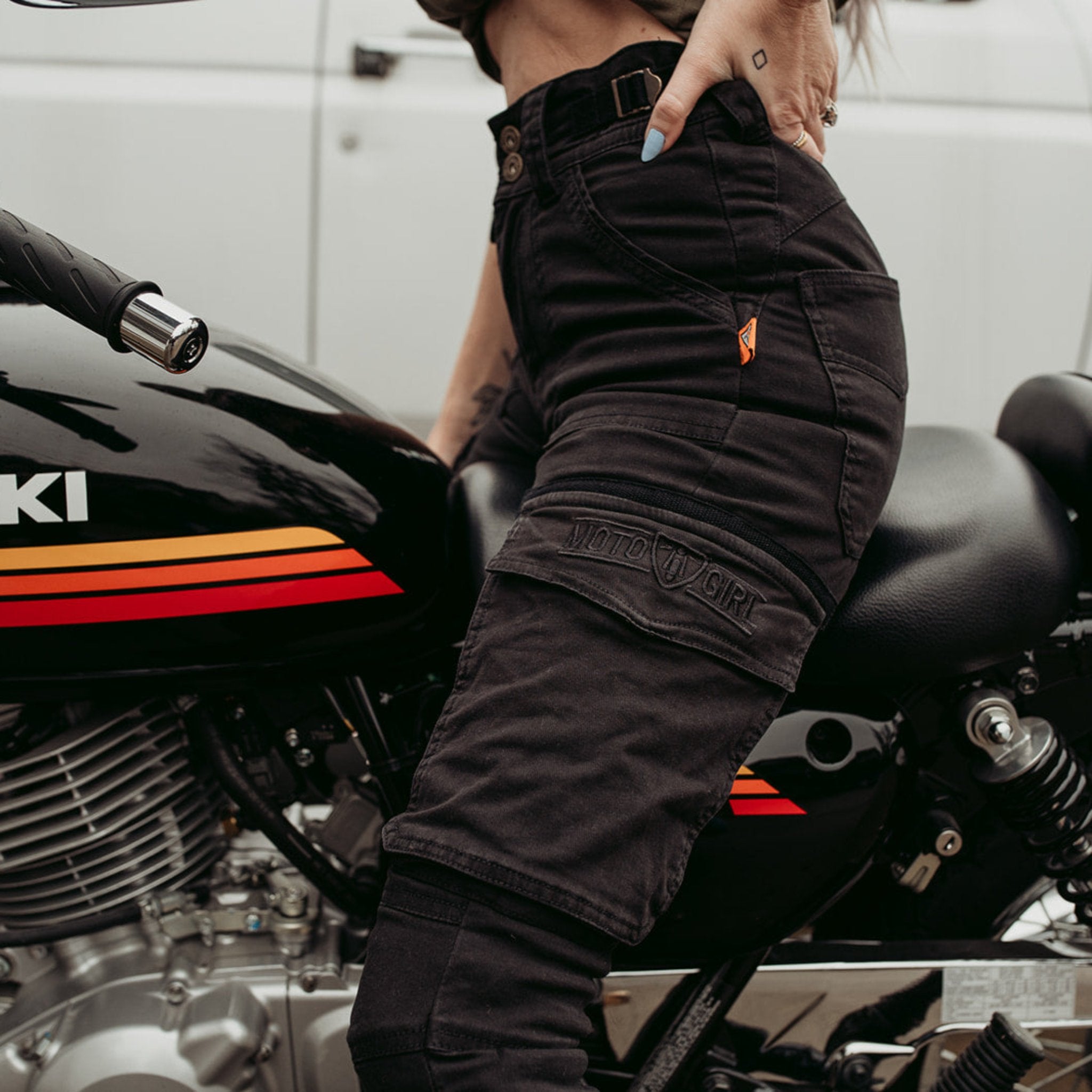 Half body of a woman siting on a motorcycle and wearing black motorcycle cargo pants from moto girl with big pockets s