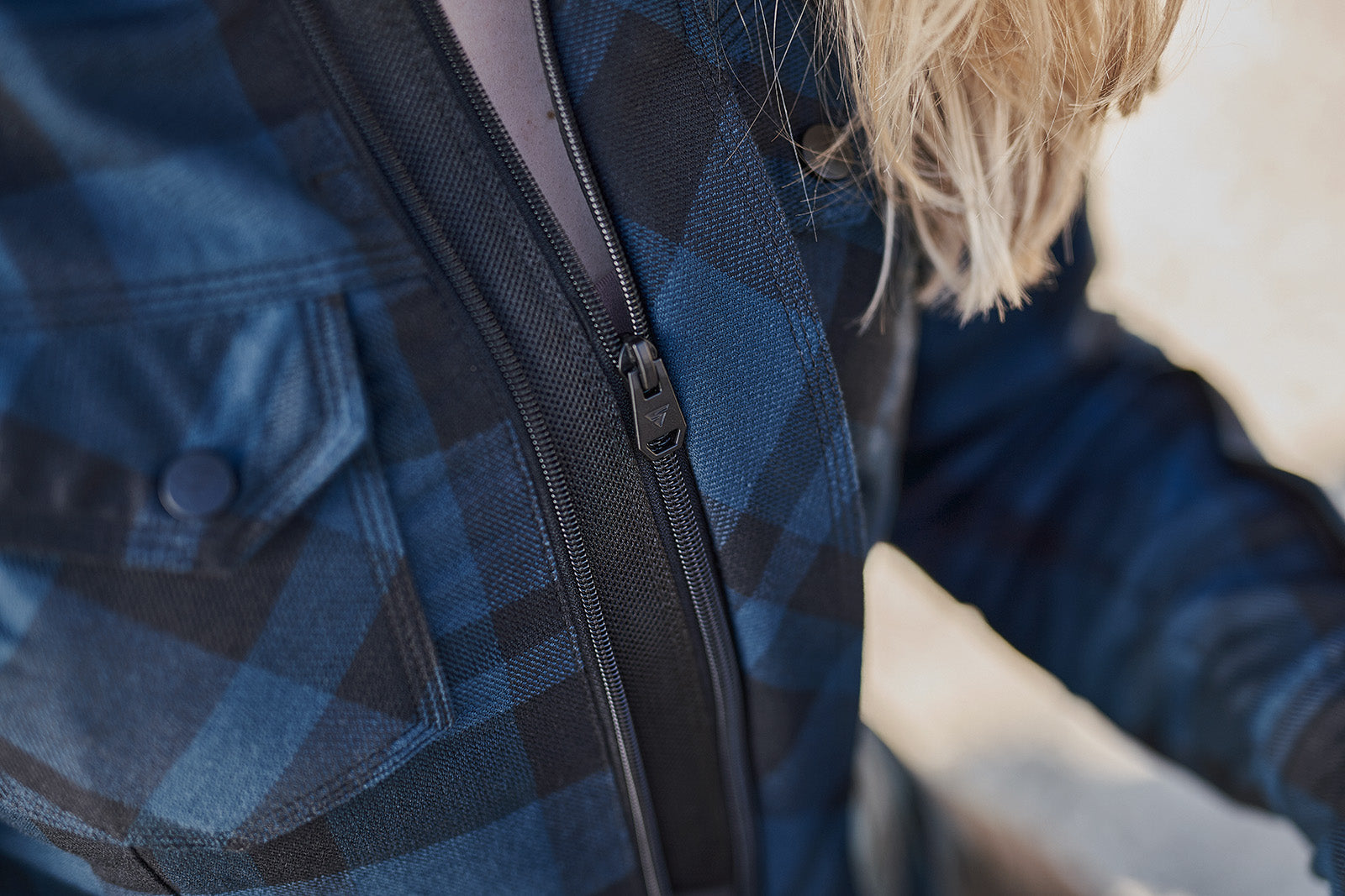 Close-up of a person wearing a blue plaid MOTORCYCLE jacket from Shima with a zipper 