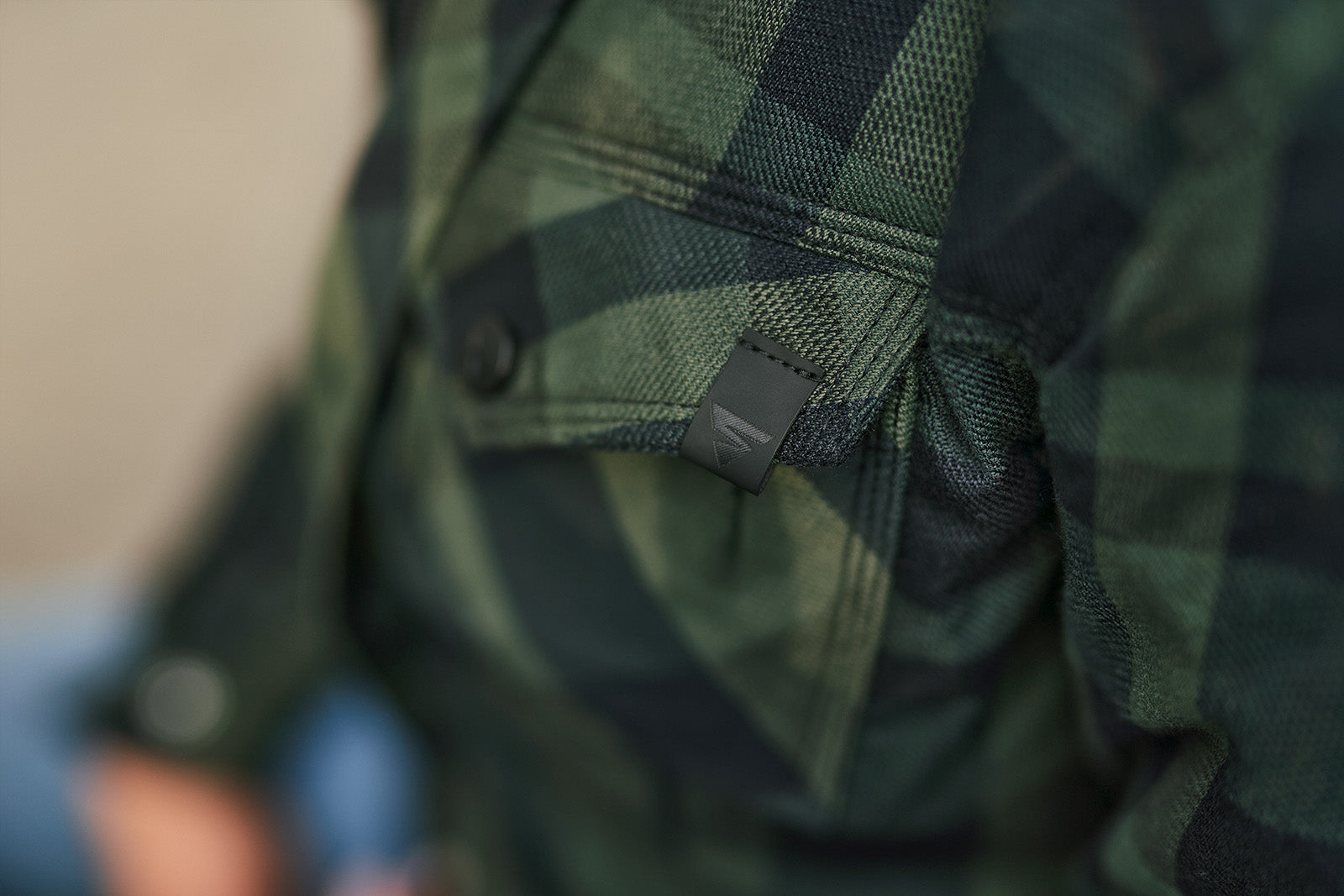 Close-up of a green plaid shirt with a tag on a blurred background