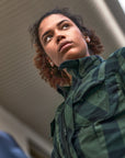 Woman in a green jacket looking up, with a blurred background