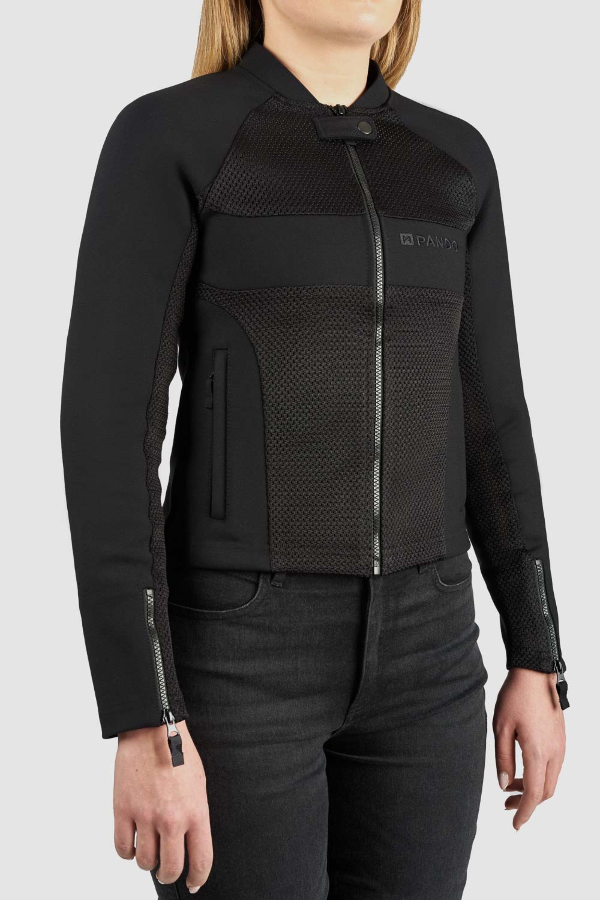 Black jacket with mesh panels worn by a person on a light gray background