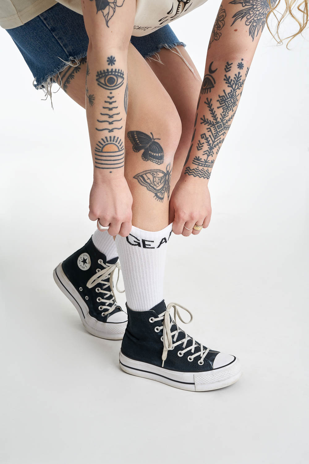 Women's tattood legs wearing white socks with  "gear" motive