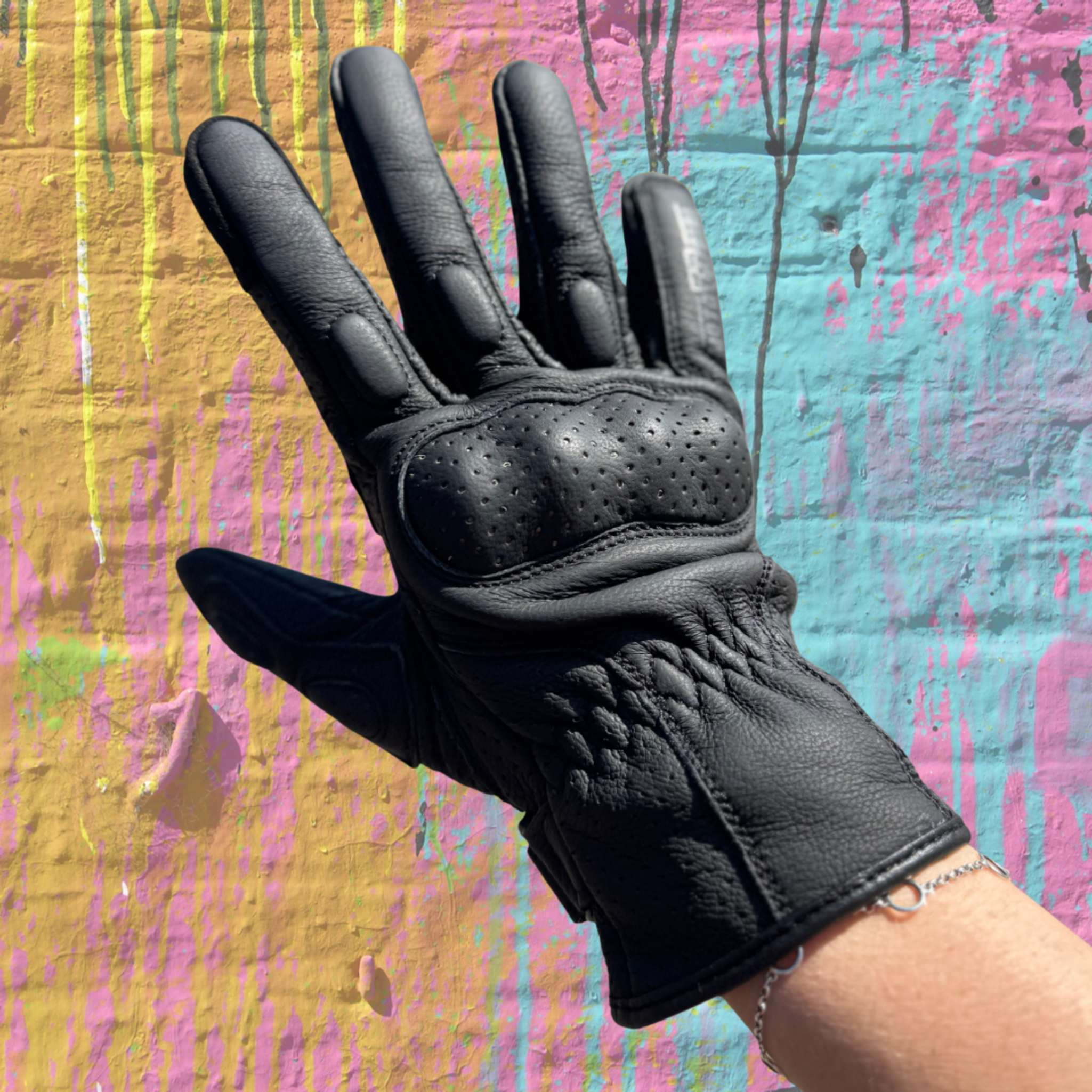 Black glove on a hand against a colorful abstract background