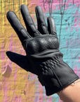 Black glove on a hand against a colorful abstract background