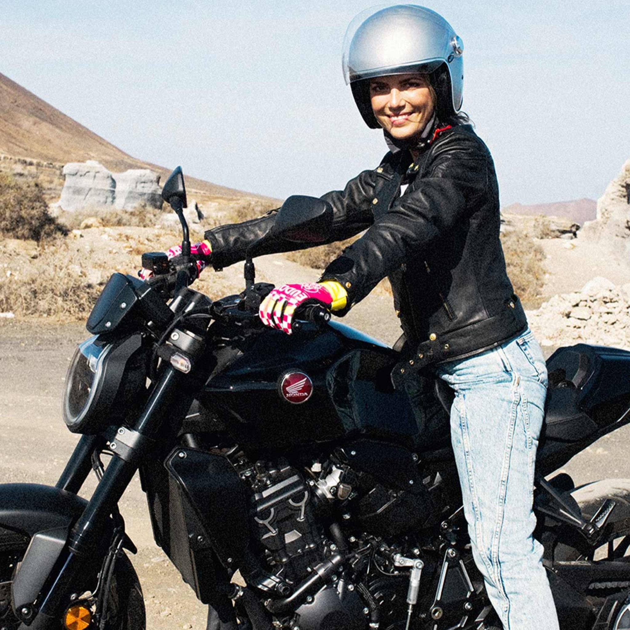 A young woman on a motorcycle wearing Classic retro black women's motorcycle jacket from Eudoxie