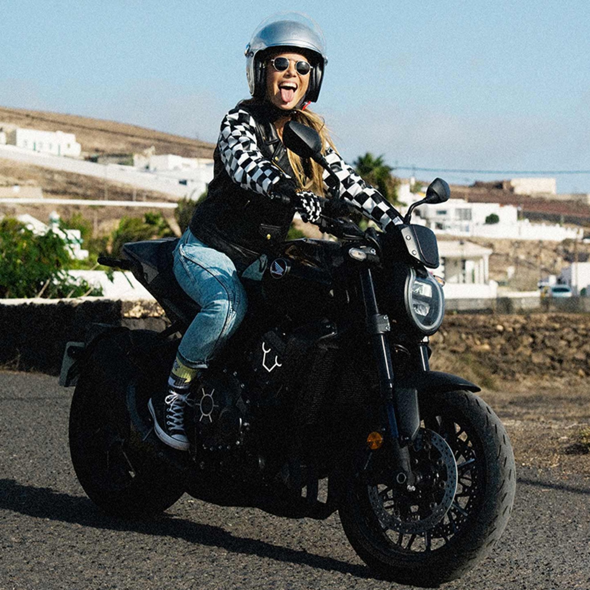 A woman on a motorcycle wearing a Chessboard design leather motorcycle jacket from eudoxie