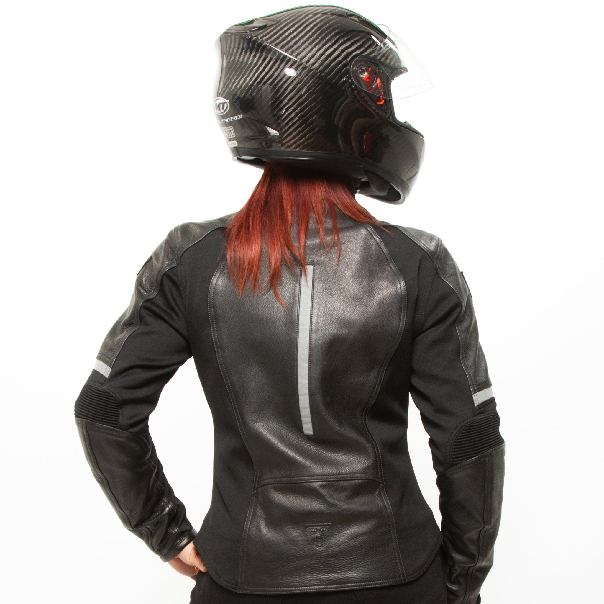 A red-haired woman wearing a helmet posing in a black leather women's motorcycle jacket with reflectors from Moto Girl