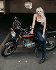 A tattooed woman on her Suzuki motorcycle wearing blue lady motorcycle jeans from Moto Girl.