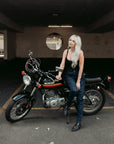 A tattooed woman on her Suzuki motorcycle wearing black lady motorcycle jeans from Moto Girl.