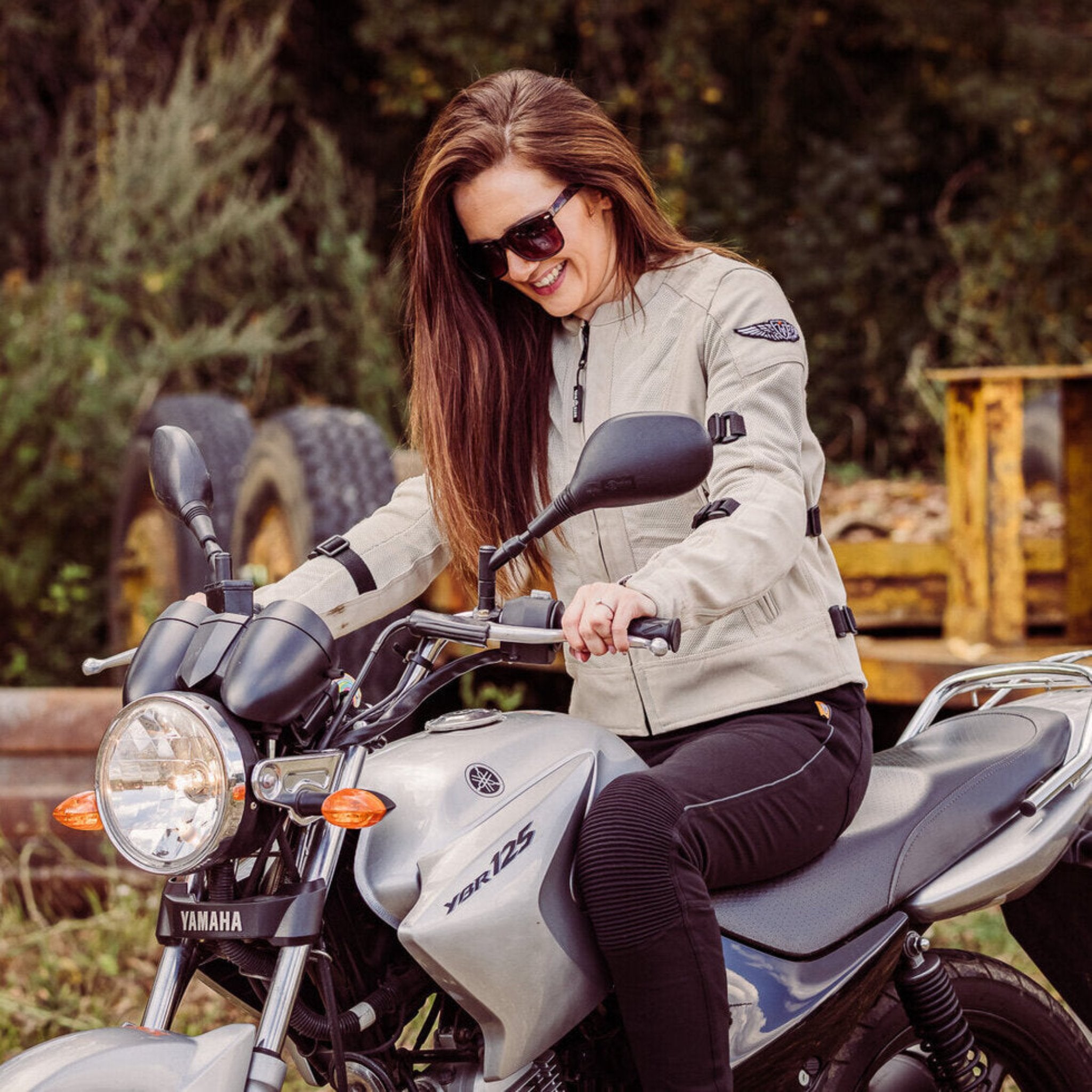 smiling woman sitting on a Yamaha motorcycle while wearing Jodie mesh mc jacket in natural from moto girl