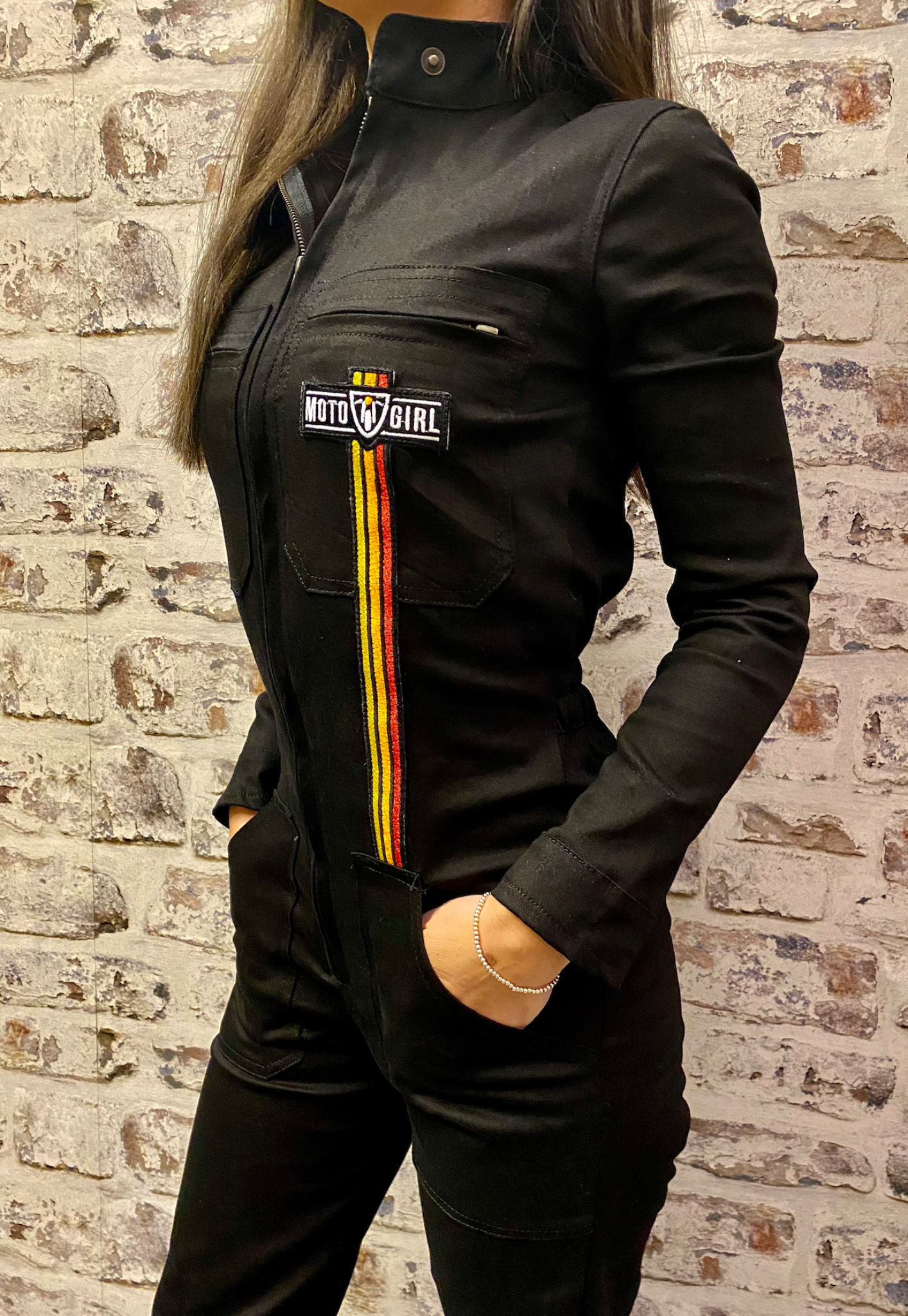 A dark haired woman wearing black garage suit for women from MotoGirl with stripe details