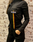 A dark haired woman wearing black garage suit for women from MotoGirl with stripe details