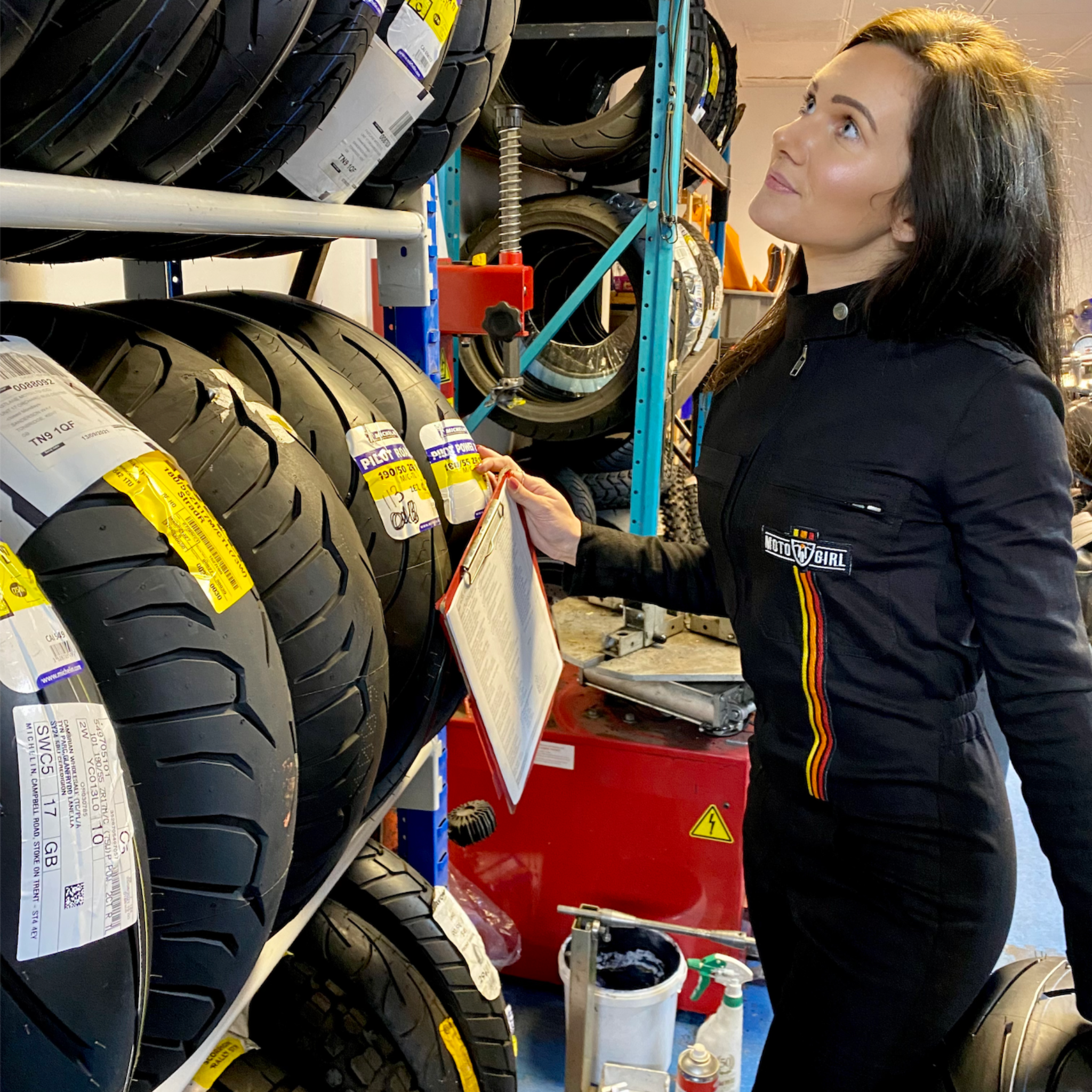 A woman wearing black garage suit for women from MotoGirl working in the motorcycle shop