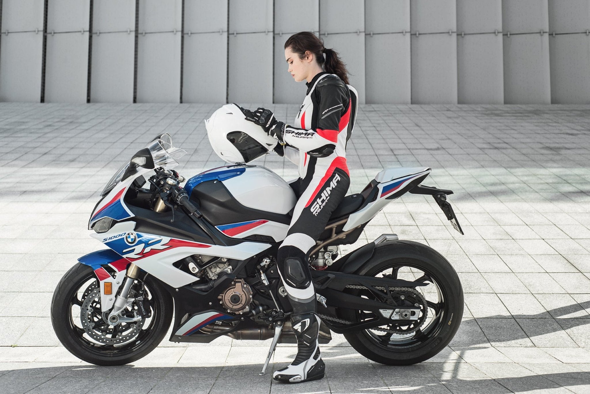 A young woman on a bmw racing motorcycle wearing Women's racing suit MIURA RS in black, white and fluo from Shima  