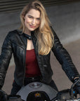 A blond woman on a motorcycle wearing Black leather motorcycle jacket for women from Shima