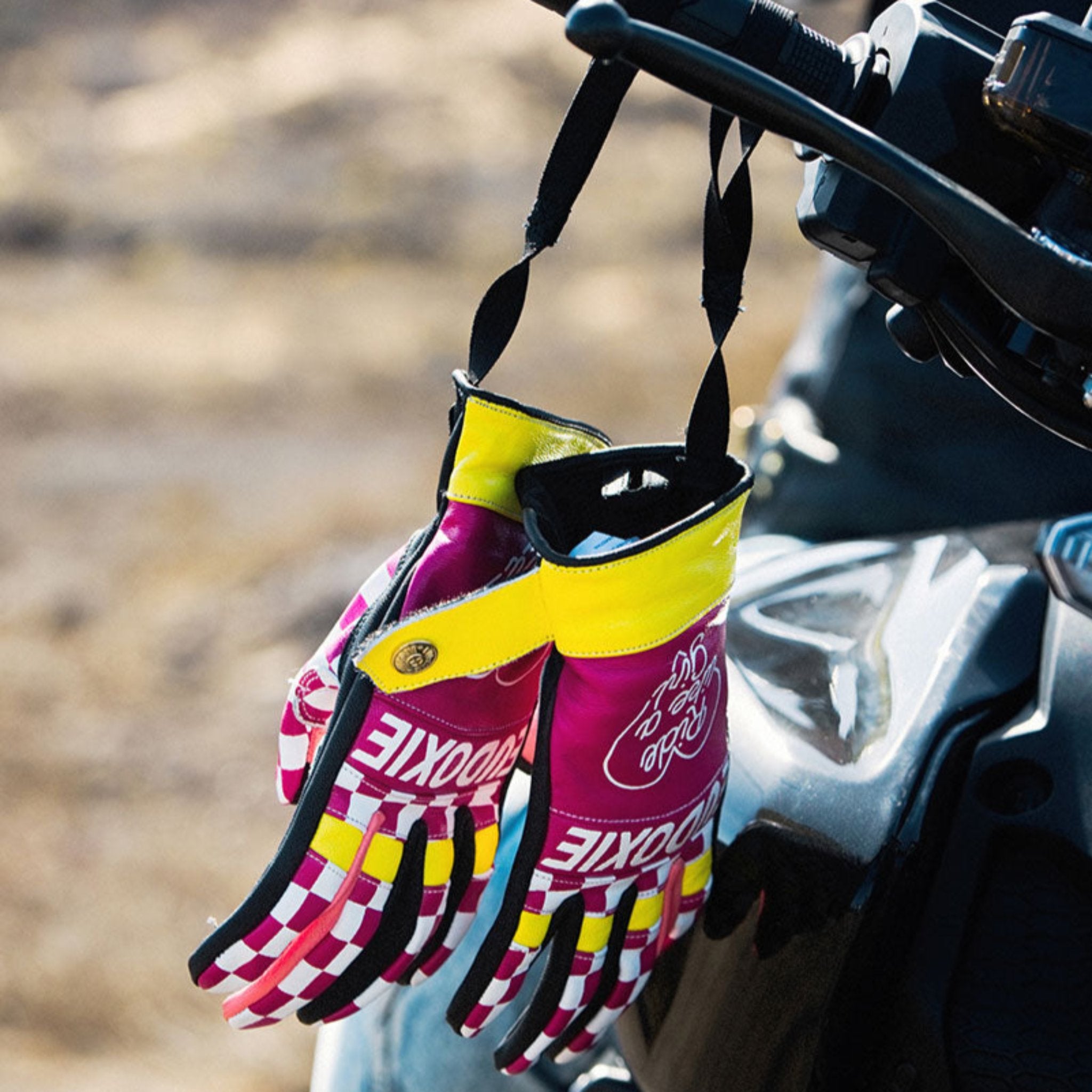 Ride like a Girl pink, black and yellow women&#39;s motorcycle gloves from eudoxie hanging on a motorcycle 